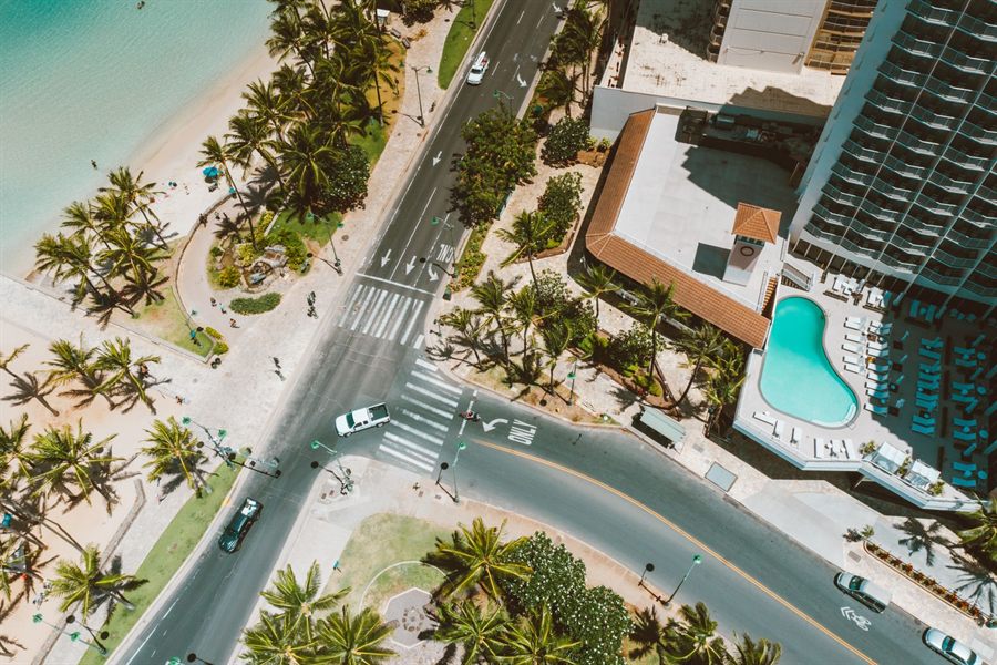 Aerial view of a beachfront hotel pool and palm-lined street in Waikiki